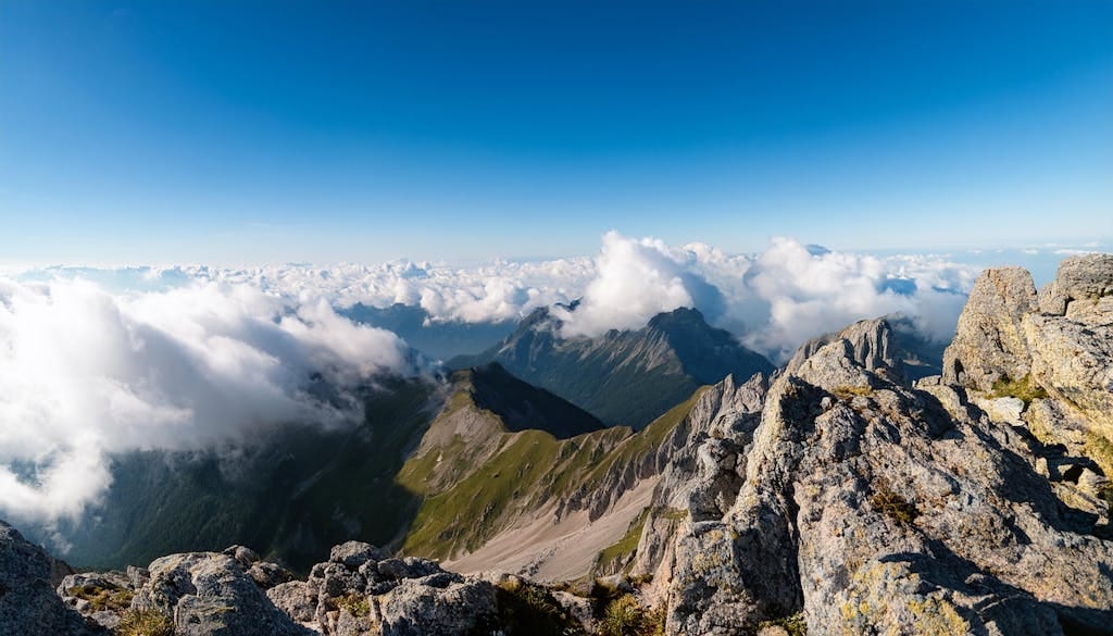 Panoramic view of a rugged alpine mountain with clouds and clear blue sky.